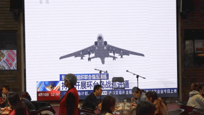 Pelanggan bersantap di dekat layar raksasa yang menyiarkan cuplikan berita pesawat Angkatan Udara di bawah Komando Teater Timur Tentara Pembebasan Rakyat China (PLA) yang ikut serta dalam patroli kesiapan tempur dan latihan "Joint Sword" di sekitar Taiwan, di sebuah restoran di Beijing, Tiongkok 10 April 2023 [Tingshu Wang/Reuters]