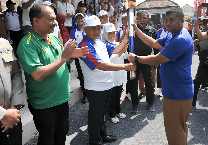 Bupati Malang, M. Sanusi, secara simbolis menerima obor Api Porprov Jatim IX 2025 dari Ketua PB Porprov, Dedi Suhayadi, saat kirab api obor tiba di Kantor Kecamatan Lawang, Senin (23/06/2025). Ribuan warga Lawang menyambut antusias kedatangan obor, yang menjadi penanda dimulainya rangkaian Porprov Jatim di Malang Raya.