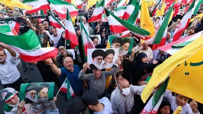 Warga Iran meneriakkan slogan-slogan, mengibarkan bendera nasional, dan memegang potret Pemimpin Tertinggi Iran Ayatollah Ali Khamenei (kiri) dan mendiang Pemimpin Tertinggi Ayatollah Ruhollah Khomeini, saat mereka merayakan gencatan senjata antara Iran dan Israel di Lapangan Enghelab di ibu kota Teheran pada 24 Juni 2025.