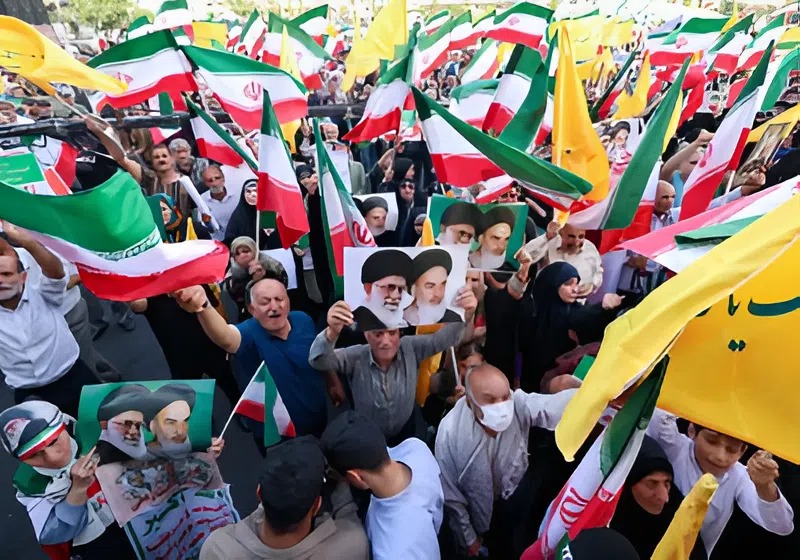 Warga Iran meneriakkan slogan-slogan, mengibarkan bendera nasional, dan memegang potret Pemimpin Tertinggi Iran Ayatollah Ali Khamenei (kiri) dan mendiang Pemimpin Tertinggi Ayatollah Ruhollah Khomeini, saat mereka merayakan gencatan senjata antara Iran dan Israel di Lapangan Enghelab di ibu kota Teheran pada 24 Juni 2025.